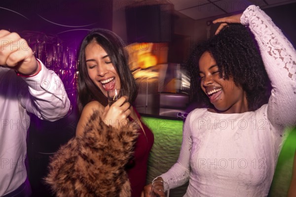 Diverse group of young women friends having fun laughing and celebrating together, enjoying the vibrant nightlife in a dimly lit club with colorful lights