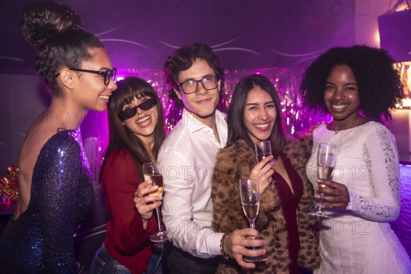 Diverse group of smiling friends celebrating together during a festive event, holding champagne glasses in a lively nightclub with vibrant purple lighting creating a party atmosphere
