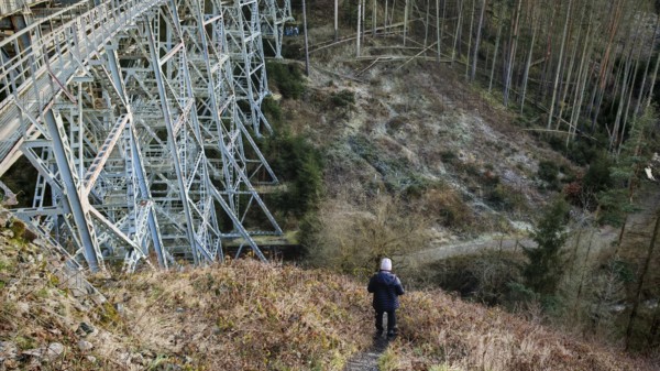 Hikers on a path next to a large metal-textured bridge, old railroad bridge in the forest, Ziemestalbrücke, Thuringian Forest