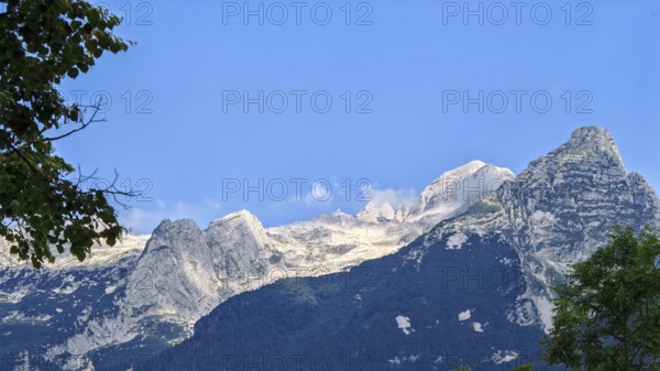 Mountains under clear blue sky, rocky peak in foreground, Slovenia