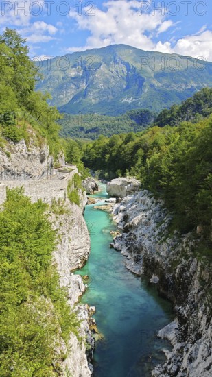 Gorge with clear water and surrounding green mountains under blue sky, Soca Valley, Slovenia