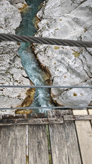 Wooden bridge over turquoise river between bright, rocky banks, Soca Valley, Slovenia