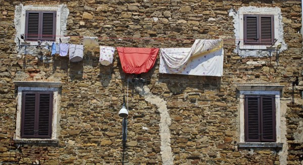 Rustic stone façade with hanging linen and several dark windows, Slovenia
