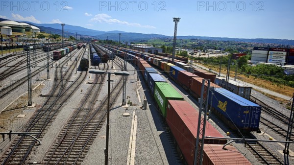 Large freight yard with lots of containers and train tracks under a blue sky, Slovenia