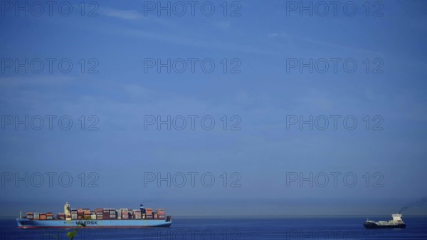 Large cargo ship full of containers on open sea with clear blue sky, Slovenia