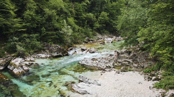 Clear river with rocks and green forest in the background, calming natural landscape, Soca valley, Slovenia