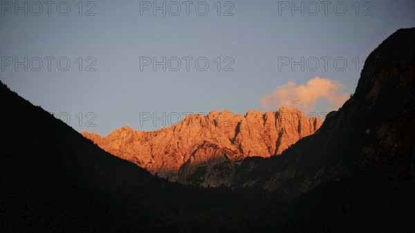 Mountains at sunset with golden rocks, alpine glow, and dark silhouettes in the foreground, Slovenia