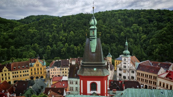 View of a town with church tower and historic buildings in front of a forest, Loket, Czech Republic