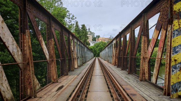 Old, rusty metal railroad bridge leads through green forests to a remote small town, Loket, Czech Republic