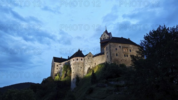 Illuminated castle at dusk against a blue sky, Loket, Czech Republic