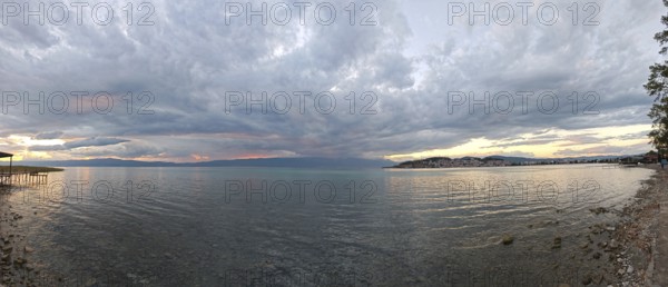 Wide panorama of a lake at sunset, with dramatic clouds in the sky, Lake Ohrid, North Macedonia