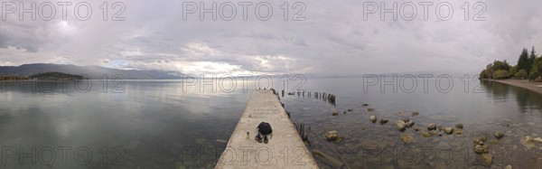Panoramic picture of a long jetty over a wide, calm lake, Lake Ohrid, North Macedonia