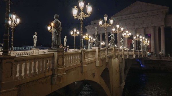 Illuminated bridge at night with statues and decorative lamps, Skopje, North Macedonia
