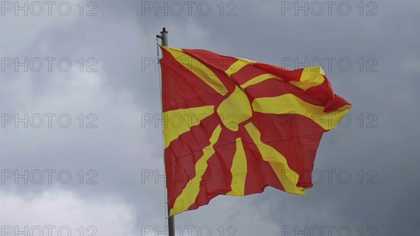 Macedonian flag, red with yellow sun, blowing against cloudy sky, North Macedonia