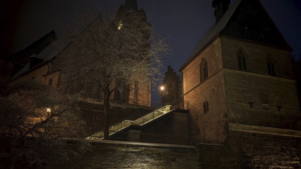 Illuminated church in the dark, surrounded by trees, conveys medieval atmosphere, view of Kronach, Frankenwald nature park Park
