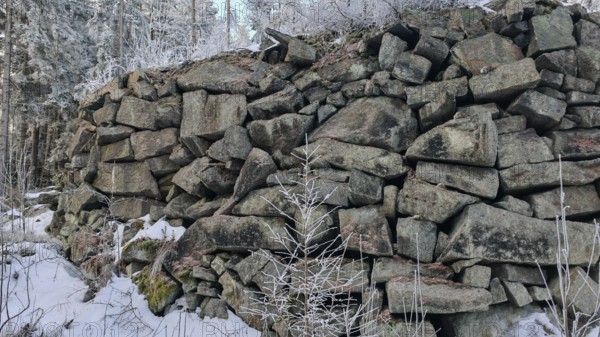Large stone wall in snowy forest, grey and cold winter landscape, Fichtelgebirge