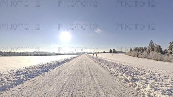 Wide snowy landscape under blue sky with bright sunshine, snowy road, Fichtelgebirge