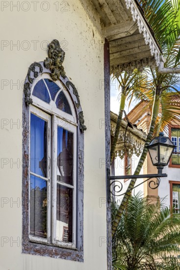 Old window decorated with a sculpture of a face and other ornaments in a historic house in the city of Ouro Preto, Ouro Preto, Minas Gerais, Brazil