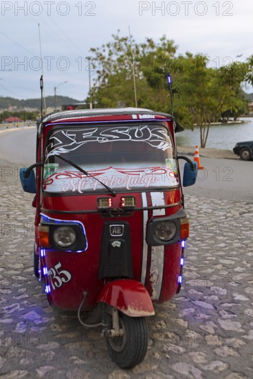 Red tuk tuk or tricycle taxi in Flores, Petén Department, Guatemala