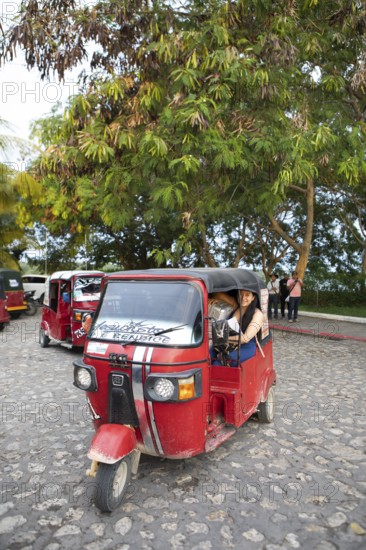 Red tuk tuks or tricycle taxis in Flores, Petén Department, Guatemala