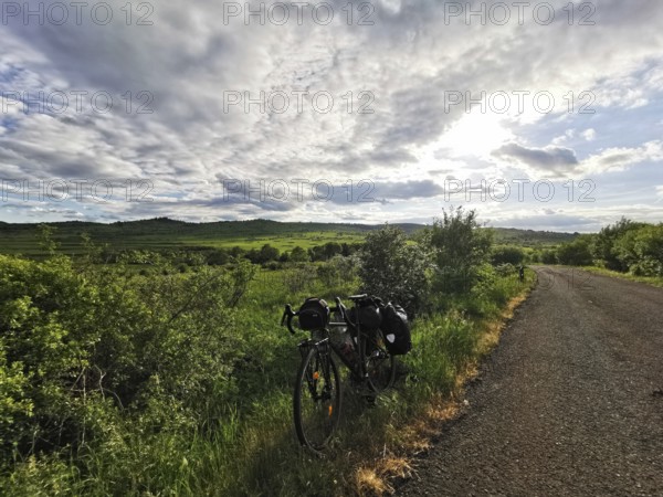 Bicycle along a rural trail with vast green fields and dramatic skies, Czech Republic