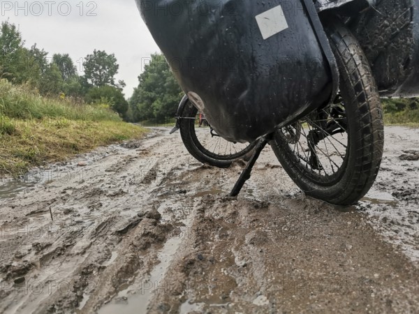 A bicycle is parked on a muddy and wet path, Poland