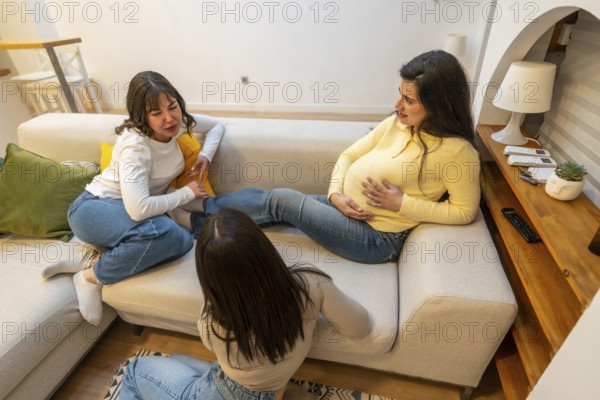Pregnant woman resting on a sofa. Communicating with her friends. Receiving support and comfort during her pregnancy journey. Creating a warm moment of female bonding and connection in the living room