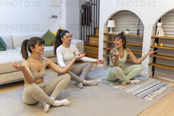 Three young women sitting in a modern living room discovering happiness through friendship and practicing mindfulness and wellness while enjoying a balanced and healthy lifestyle