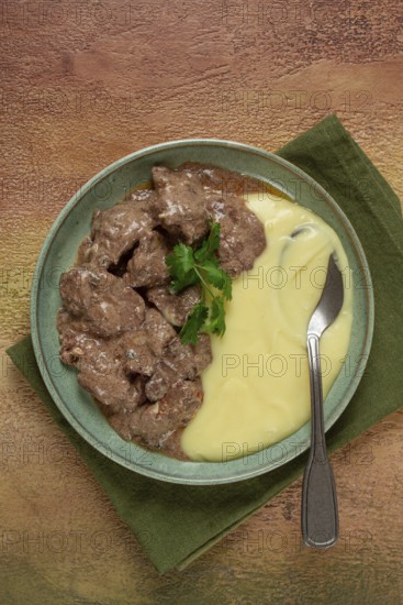 Liver beef stroganoff with mashed potatoes, table setting in green tones, homemade