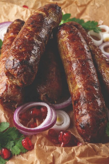 Fried kupaty on parchment, with red onion and pomegranate, kupaty, Georgian cuisine