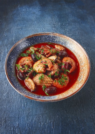 Seafood in tomato sauce with olives, on a dark blue background