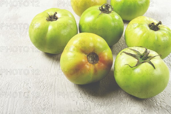 Green tomatoes scattered on the table, unripe tomatoes, raw, selective focus, no people