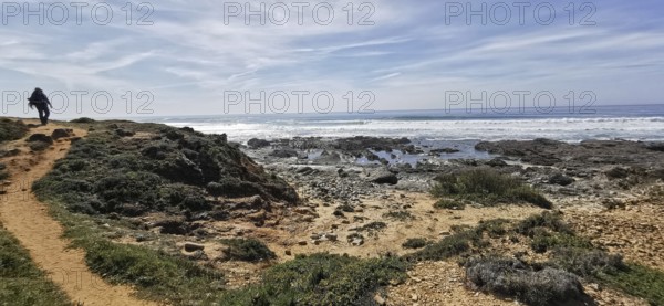 A hiker on a trail next to the rocky coast, Southwest Alentejo Natural Park and Vicentina Coast, Portugal