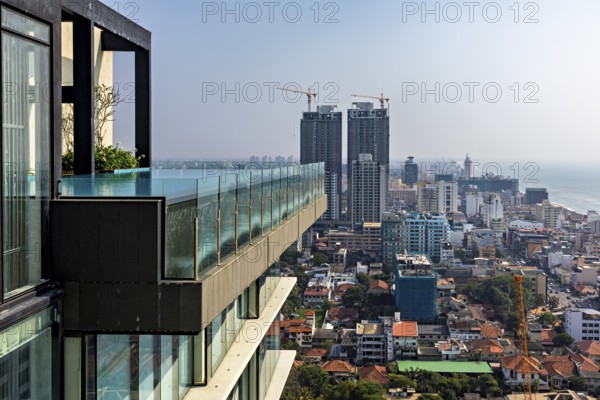Urban view with modern high-rise buildings and a pool on the edge of a building with sea views