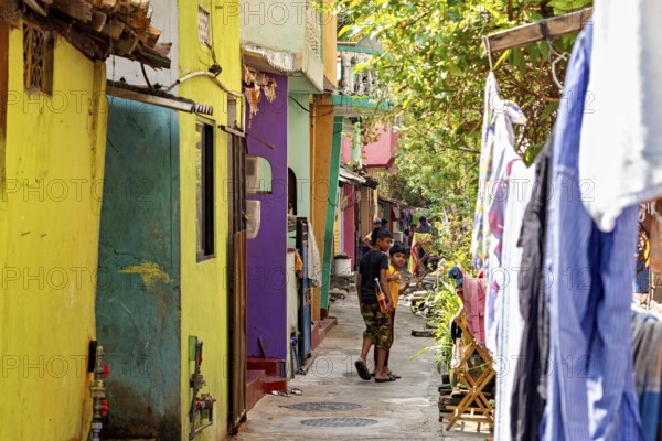 Colourful alley with children playing and hanging clothes, lively and warm