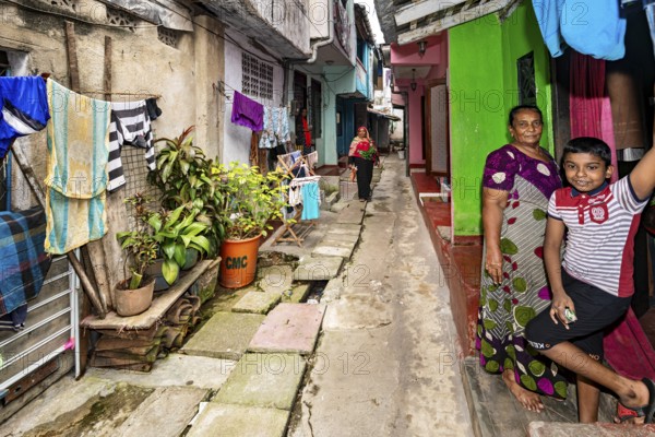 People in front of colorful houses in an alley with laundry hanging in the foreground