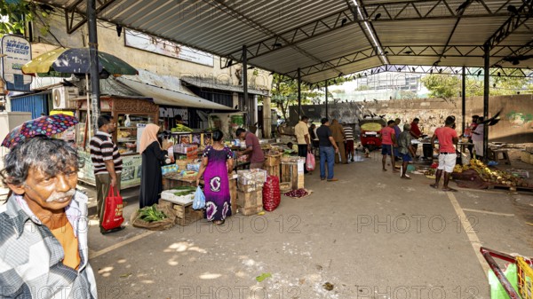 Busy street market with market stalls and people under one roof in an urban environment