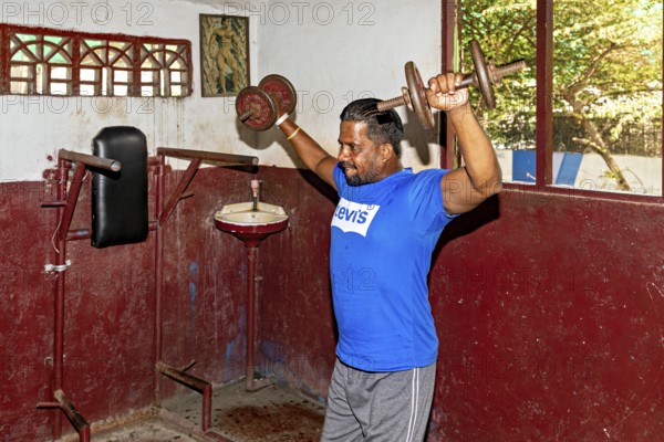 Man weightlifting in a traditional gym, focus on building muscle