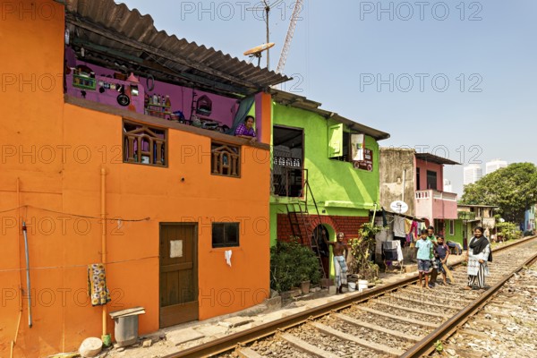 Colourful houses along railroad tracks on a sunny day with local people