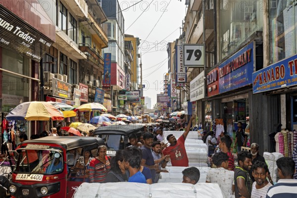 Close-traffic street market with people, rickshaws and colorful shop facades, the hustle and bustle of Colombo city center in Sri Lanka