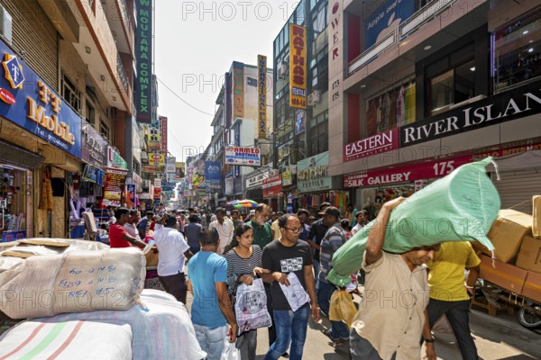 Well-visited shopping street with numerous people and payloads in bright sunlight, the hustle and bustle in the city center of Colombo in Sri Lanka