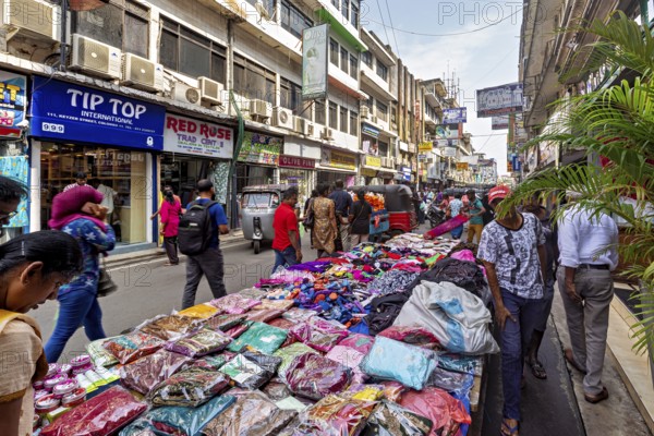 Street market with laid-out clothes and busy foot traffic, the hustle and bustle of Colombo city center in Sri Lanka