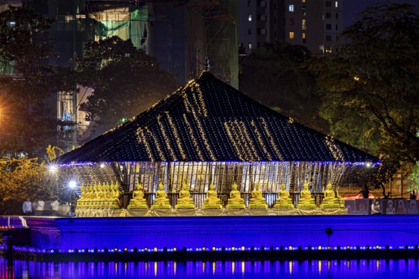 A temple shrouded in lights with golden Buddha statues at night, The Seema Malaka Temple in Colombo in Sri Lanka