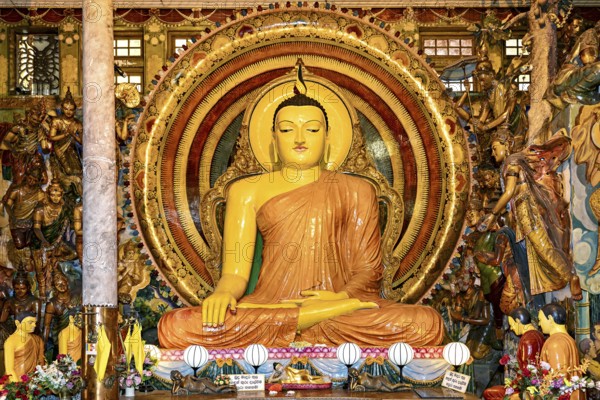 Buddha statue in meditating posture surrounded by ornate gold decoration and spiritual symbols in the temple, Buddha statue in the temples of Colombo in Sri Lanka