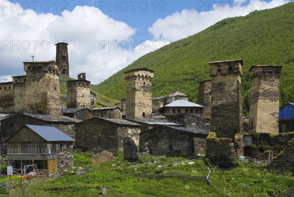 Medieval stone towers and buildings in front of a wooded mountain and cloudy sky, defensive towers, Ushguli, Chazhashi district, Mingrelia region and Upper Svaneti, Svaneti, Georgia