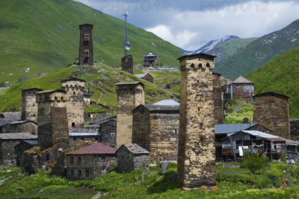 Historic mountain village with distinctive stone towers surrounded by green hills under a cloudy sky, defensive towers, Ushguli, Ushguli, Chazhashi district, Mingrelia region and Upper Svaneti, Svaneti, Georgia