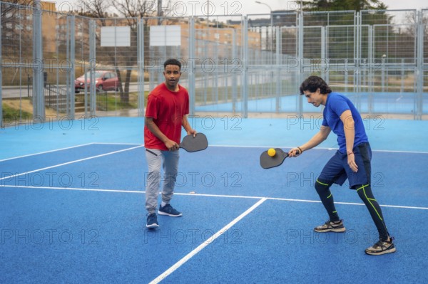 Two men intensely competing in pickleball on a vibrant blue outdoor court, focused and athletic as they rally with paddles and ball in a dynamic, energetic match
