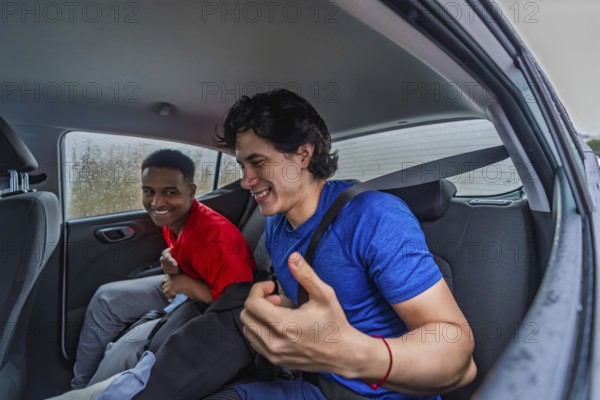 Two smiling diverse men friends wearing sportswear and fasten seatbelt in a car, traveling together and preparing for a pickleball game on a rainy day