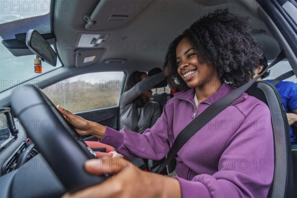 Smiling black woman driving with diverse friends, enjoying a carefree road trip, candid in car moment conveying happiness, connection, freedom and shared adventure