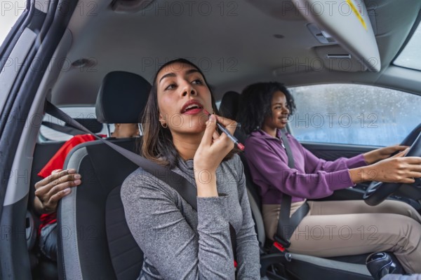 Women friends traveling together in a car, with a passenger applying lipstick using a makeup pencil while the driver steers with a relaxed smile, sharing a pleasant journey